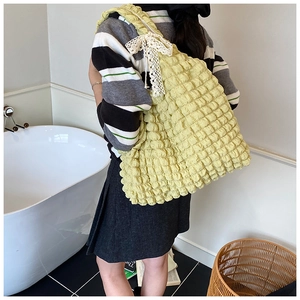 Detail of light yellow bubble tote bag with lace bow decoration and textured fabric