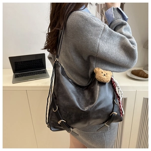 Grand sac cabas en cuir noir avec sangles décoratives et charm ours en peluche sur modèle
