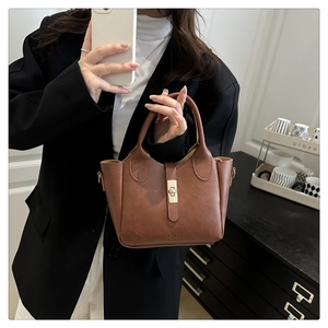 Détail du sac seau en cuir marron foncé avec fermoir doré et logo gravé sur le fond