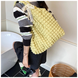 Detail of yellow bubble texture tote bag with white lace bow decoration