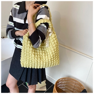 Detail of light yellow bubble fabric tote bag with elegant beige lace bow and soft texture
