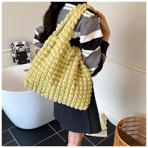 Detail of light yellow ruched bubble tote bag with elastic popcorn fabric texture