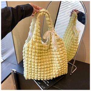 Detail of yellow popcorn texture bag featuring cream lace bow and ruched fabric design