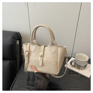 Détail du sac seau crème montrant la texture grainée et le fermoir rotatif en métal