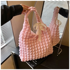 Detailed shot of pink popcorn puff bag featuring a delicate lace bow and textured fabric