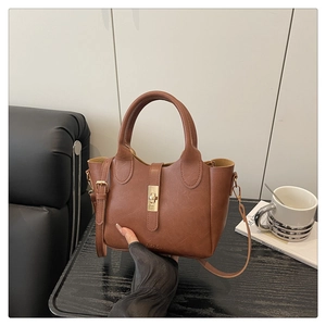 Vue détaillée du fermoir doré et du logo embossé sur le sac seau en similicuir marron