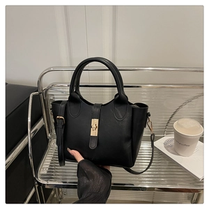 Détail d'un sac seau en cuir noir avec fermoir doré et bandoulière réglable