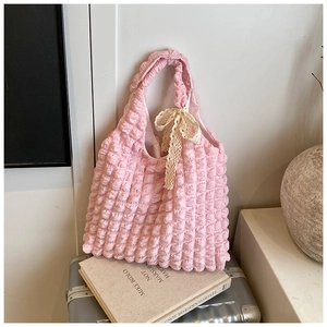 Detail of pink popcorn textured tote bag with creamy lace bow on a metallic surface