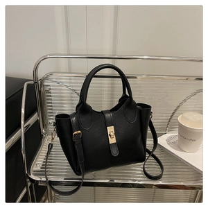 Détail du sac seau noir en similicuir avec fermoir rotatif doré et deux poignées hautes