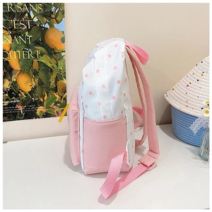 Détails latéraux du sac à dos rose et blanc à motif d'étoiles avec poche et bretelles