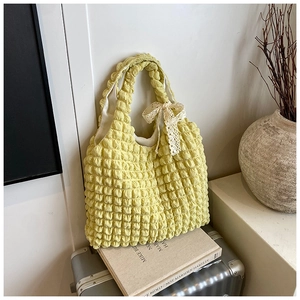 Detail of light yellow bubble texture fabric with white lace bow on the shoulder bag