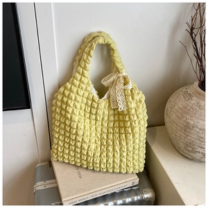 Macro detail of yellow bubble textured fabric tote bag with white lace bow decoration