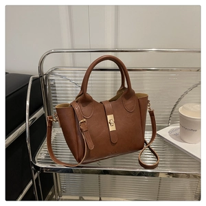 Détail d'un sac seau en cuir marron avec un fermoir doré et une bandoulière réglable