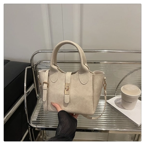 Sac seau beige chic avec fermoir doré et lettrage FASHION dans un décor de style de vie chic