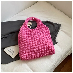 Detail of pink bubble textured puff tote bag with popcorn pleated design on white fabric