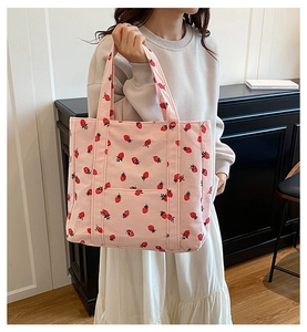 Borsa tote in velluto rosa con stampa di fragole in un ambiente interno accogliente