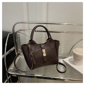 Détail du sac seau rétro marron foncé avec texture grainée et fermoir doré sur présentoir