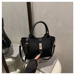 Détail du sac seau noir avec fermoir rotatif doré et texture mate et lisse élégante