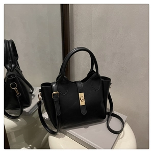 Détail du sac à main noir en cuir texturé avec un fermoir métallique doré élégant