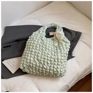 Detail of light green puffy bubble texture bag with delicate cream lace bow decoration