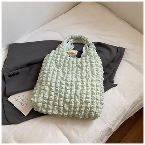 Close-up of light green popcorn texture handbag with delicate lace ribbon and bow details