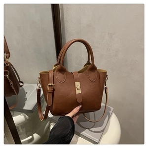 Détail du sac seau en cuir marron foncé avec fermoir doré et bandoulière réglable