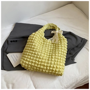 Detail of light yellow popcorn textured tote bag featuring a delicate white lace bow accent