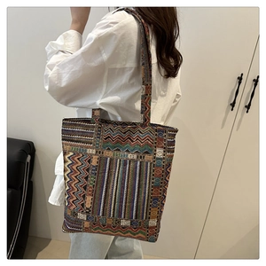 Detail of colorful woven tote bag with geometric wave pattern shown on a model
