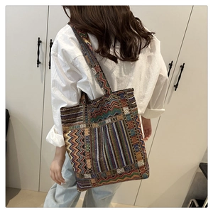 Detail of colorful geometric woven tote bag with ethnic pattern on model's shoulder