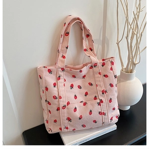 Dettaglio della borsa tote in velluto rosa con stampe di fragole su libri