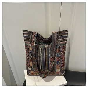 Detailed shot of ethnic woven tote bag with colorful geometric patterns on a white book