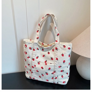 Detailed macro of strawberry print corduroy tote bag showing front pocket and texture