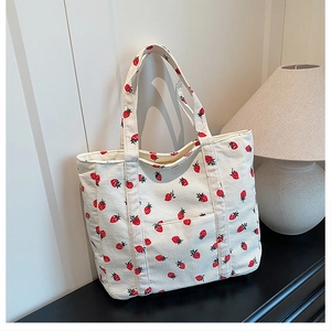 Dettaglio della borsa tote in velluto a coste con stampe di fragole e tasca frontale
