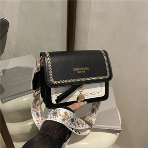 Chic black and white crossbody bag with floral embroidered strap and gold pendant
