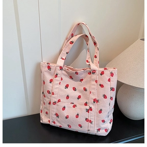 Dettaglio della borsa tote in velluto rosa con stampa di fragole rosse all-over