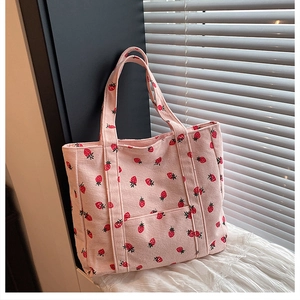 Dettaglio della borsa tote in velluto a coste rosa con stampa di fragole e cuciture