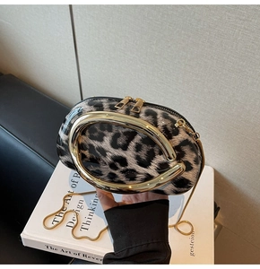 Detail of leopard print oval clutch with golden U-shaped ring and chain strap