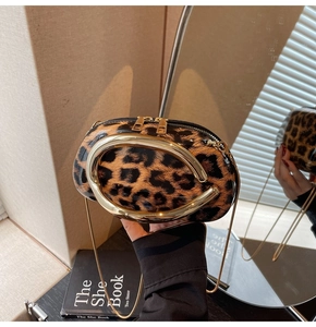 Detail of leopard print handbag with large gold oval handle and metal chain strap