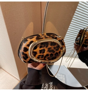 Detail of leopard print oval bag with gold C-shaped handle and metallic chain strap