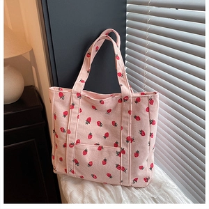 Dettaglio della borsa tote in velluto rosa con stampa fragole e tasca frontale