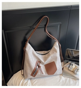 Close-up of textured canvas hobo bag with brown leather accents and modern zipper detail