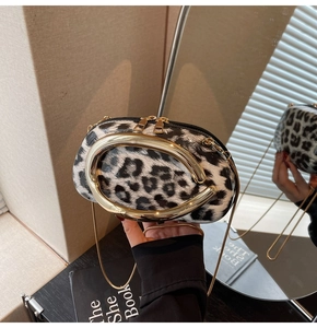 Close-up of leopard print acrylic clutch with large gold oval metal handle and chain strap
