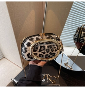 Detail of leopard print handbag featuring a large gold metal handle and chain strap