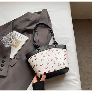 Detail of Korean style tote bag with red cherry print and black leather handles