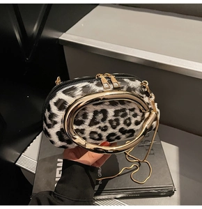 Detail of leopard print handbag featuring a gold metal ring handle and chain strap