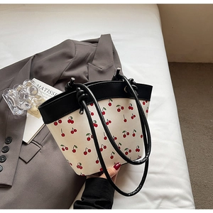 Detail of cherry print tote bag with contrast black rope handles and knotted design