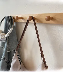 Detail of comfortable brown shoulder straps on a canvas tote bag hung on a wooden hook