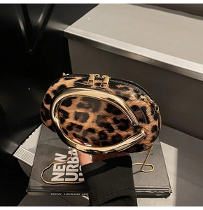 Detailed close-up of leopard print handbag featuring a bold oval gold metal handle