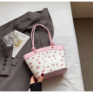 Detail of pink and white bucket bag with red cherry prints and knotted shoulder strap