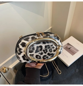Close-up of leopard print handbag with large oval gold handle and zipper details